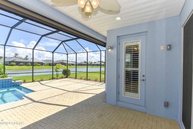 view of patio with glass enclosure, a water view, and ceiling fan