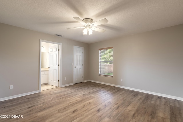 unfurnished bedroom with ceiling fan, ensuite bathroom, hardwood / wood-style floors, a textured ceiling, and a closet