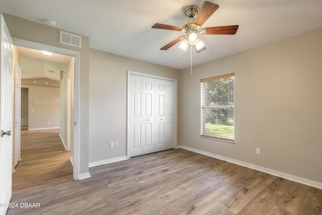 unfurnished bedroom with a textured ceiling, light wood-type flooring, a closet, and ceiling fan