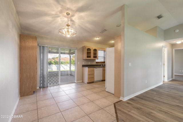 kitchen featuring lofted ceiling, white appliances, hanging light fixtures, light tile patterned floors, and a chandelier