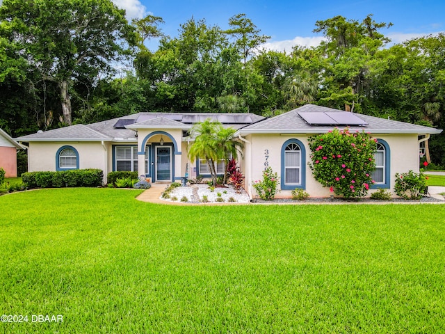 ranch-style home featuring solar panels and a front yard