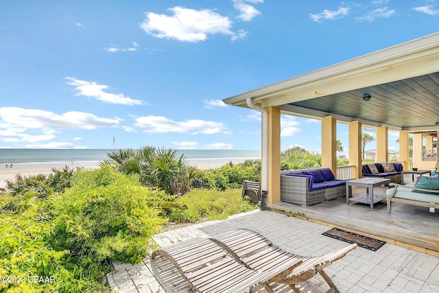 view of patio / terrace with an outdoor living space, a water view, and a view of the beach