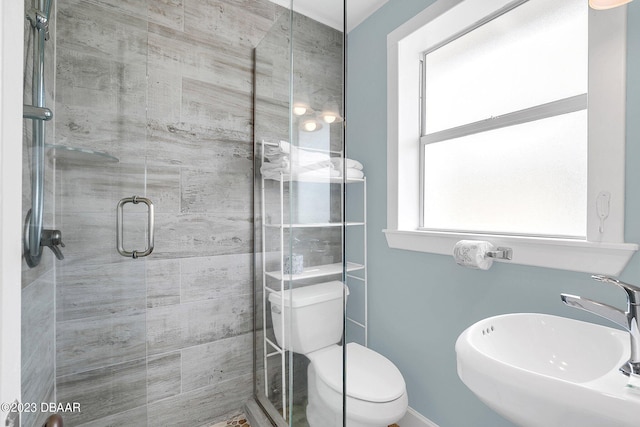 bathroom with a shower with shower door, sink, and toilet