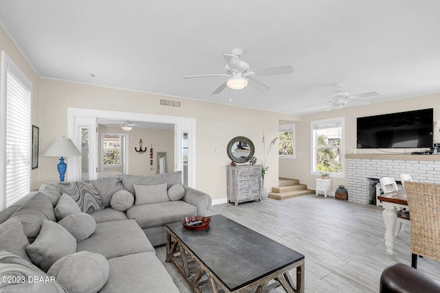 living room with plenty of natural light, ceiling fan, crown molding, and light hardwood / wood-style flooring