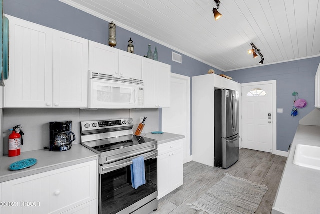 kitchen featuring stainless steel appliances, track lighting, ornamental molding, light hardwood / wood-style flooring, and white cabinets