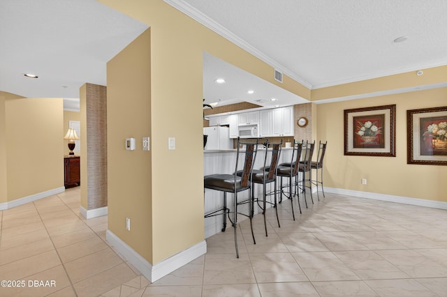 4650 Links Village Dr Unit C402, Ponce Inlet, FL 32127 - kitchen featuring white appliances, crown molding, a breakfast bar area, white cabinets, and light tile patterned floors