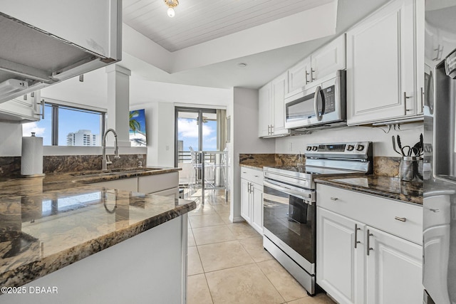 kitchen with dark stone countertops, sink, white cabinets, and stainless steel appliances