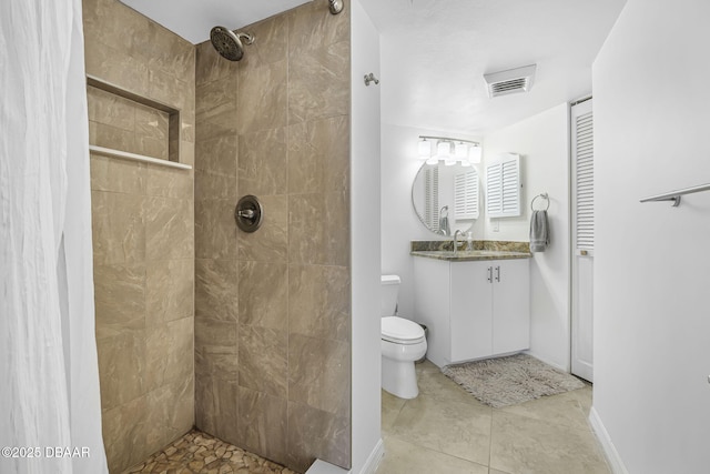 bathroom with a tile shower, tile patterned floors, vanity, and toilet