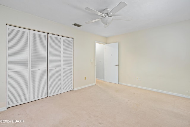 unfurnished bedroom featuring a closet, ceiling fan, and light colored carpet