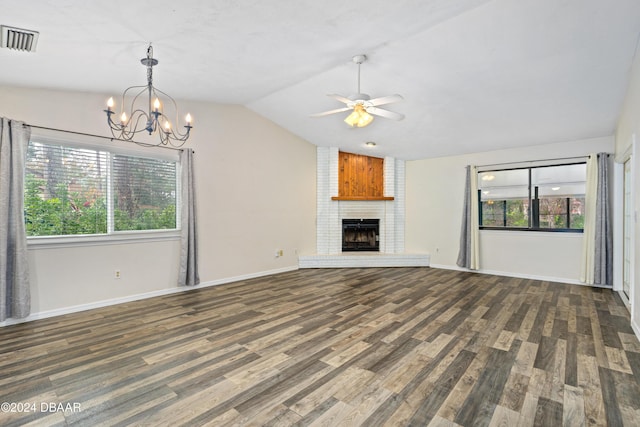 unfurnished living room featuring lofted ceiling, dark hardwood / wood-style floors, ceiling fan with notable chandelier, and a brick fireplace