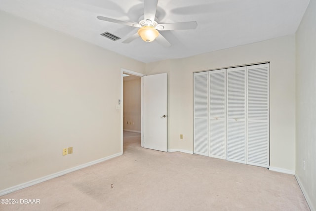 unfurnished bedroom featuring ceiling fan, a closet, and light colored carpet