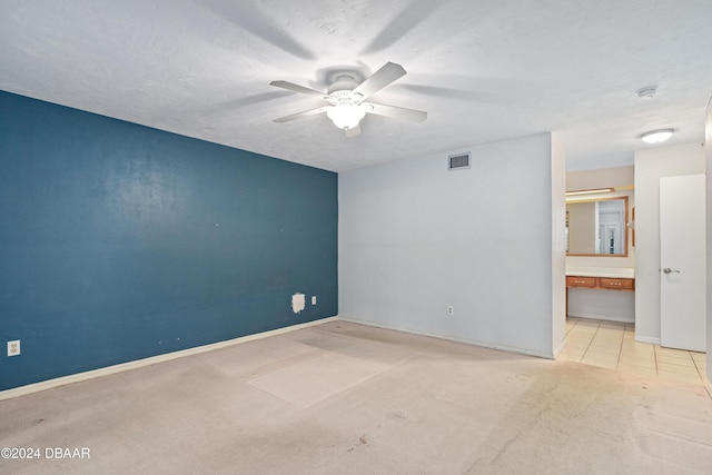 spare room with a textured ceiling, light colored carpet, and ceiling fan