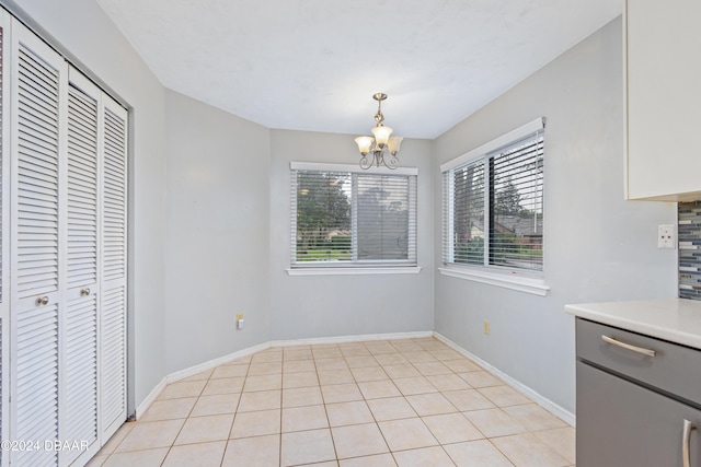 unfurnished dining area featuring light tile patterned floors and a notable chandelier