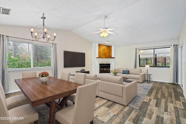 interior space with lofted ceiling, hardwood / wood-style flooring, ceiling fan with notable chandelier, and a brick fireplace