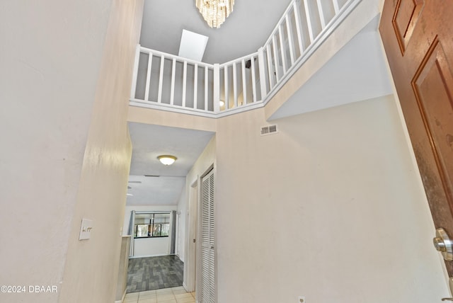 interior space with a chandelier, a towering ceiling, and light tile patterned flooring