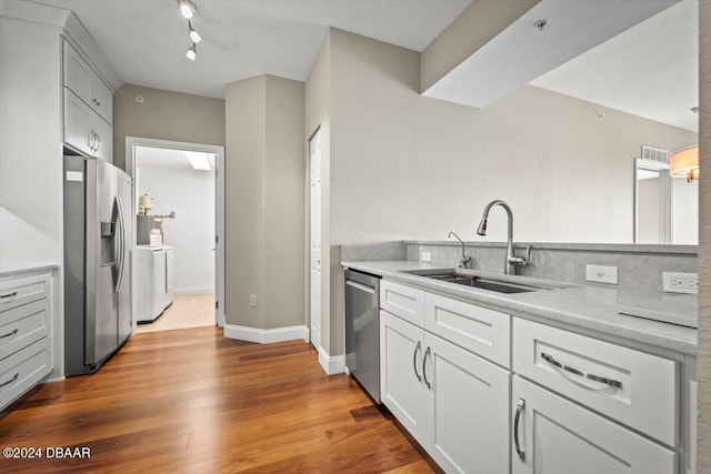 kitchen with sink, separate washer and dryer, light hardwood / wood-style flooring, white cabinets, and appliances with stainless steel finishes