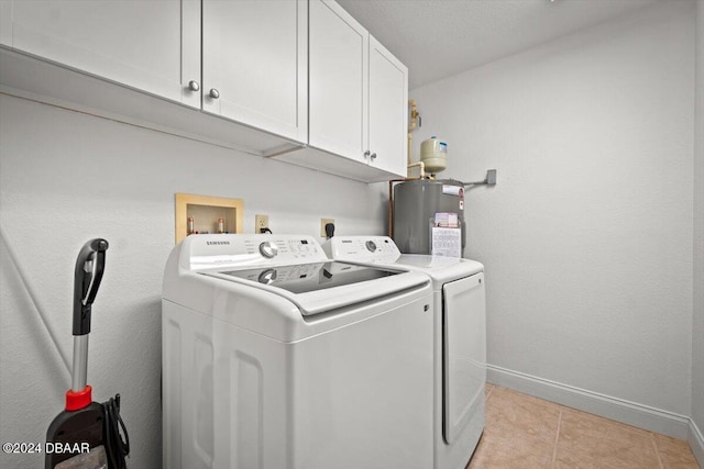 washroom with cabinets, light tile patterned floors, washing machine and dryer, and water heater