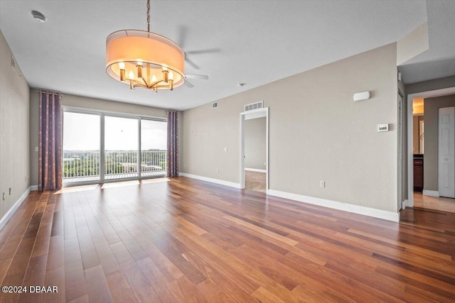 unfurnished room featuring ceiling fan with notable chandelier and wood-type flooring