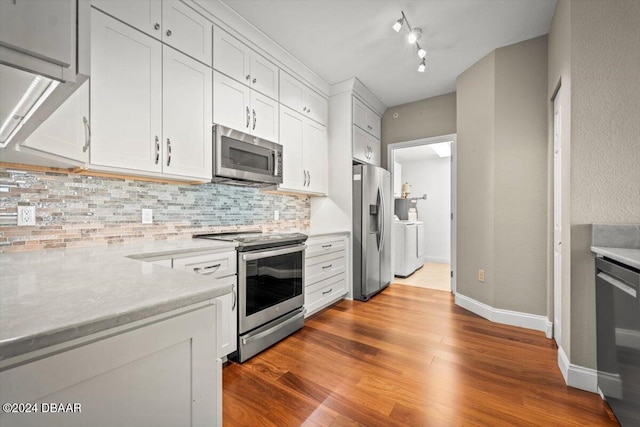 kitchen featuring stainless steel appliances, independent washer and dryer, light hardwood / wood-style floors, decorative backsplash, and white cabinets