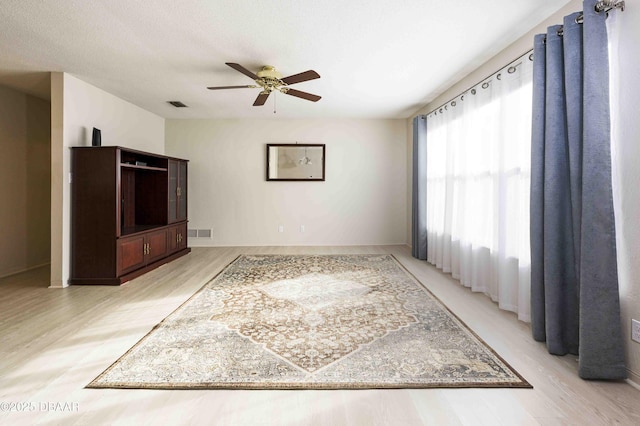 unfurnished living room with ceiling fan, a textured ceiling, and light wood-type flooring