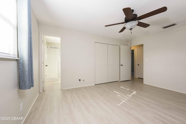 unfurnished bedroom with a closet, ensuite bathroom, ceiling fan, and light wood-type flooring