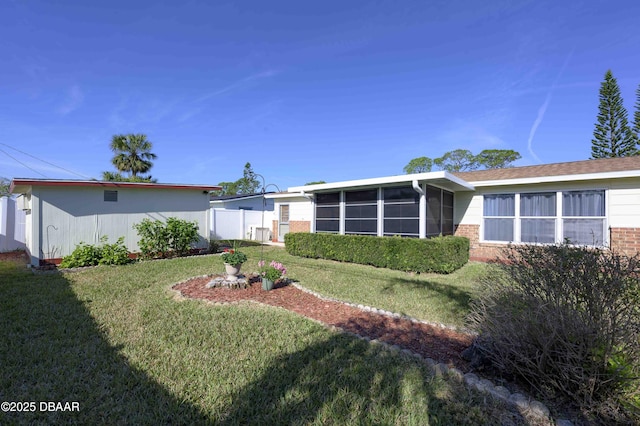 back of house featuring a sunroom and a lawn