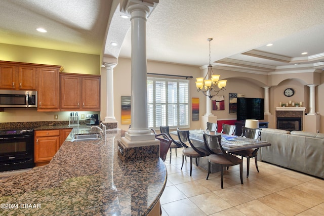 tiled dining space with decorative columns, ornamental molding, a textured ceiling, sink, and a notable chandelier