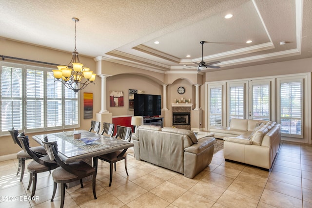 dining room featuring a tray ceiling, plenty of natural light, and decorative columns