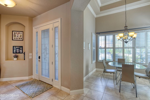 foyer featuring light tile patterned floors, a textured ceiling, and a notable chandelier