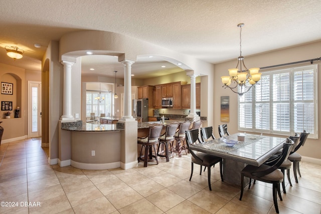 dining area with a notable chandelier, light tile patterned flooring, and a textured ceiling