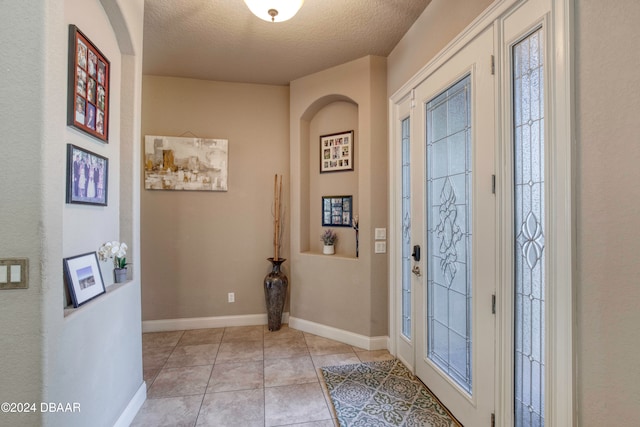 foyer featuring light tile patterned floors and a textured ceiling