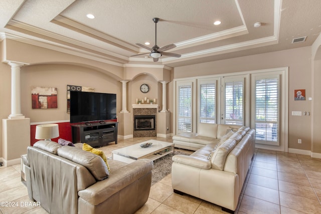 living room featuring a tray ceiling, light tile patterned floors, a textured ceiling, and ornamental molding