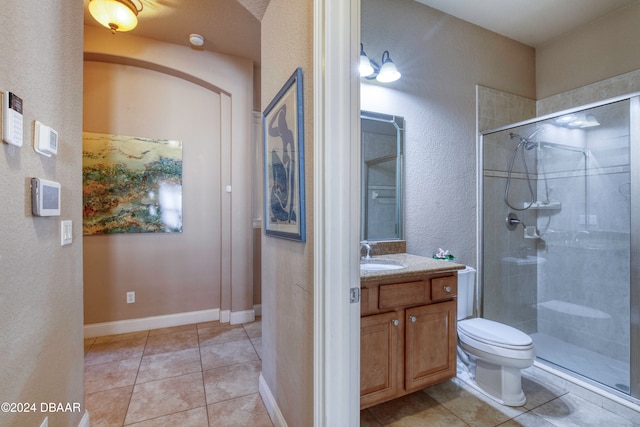 bathroom featuring tile patterned floors, toilet, vanity, and walk in shower