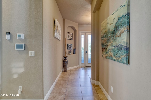 hallway featuring a textured ceiling and light tile patterned flooring