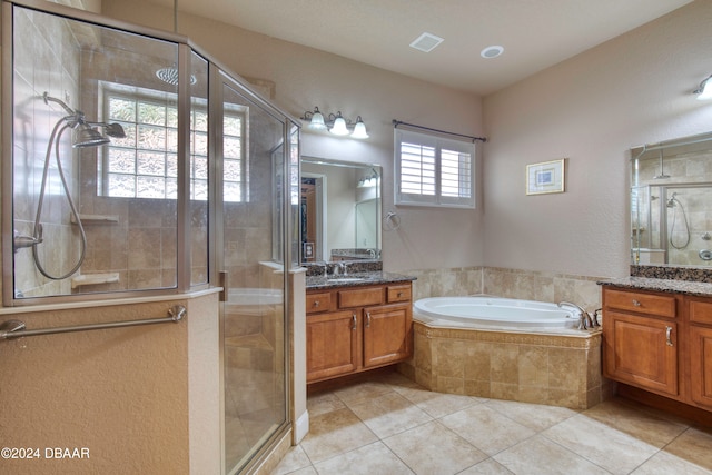 bathroom featuring plus walk in shower, vanity, a wealth of natural light, and tile patterned flooring