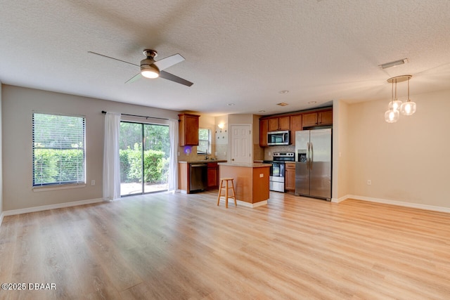 209 Tarracina Way, Daytona Beach, FL 32117 - kitchen featuring open floor plan, brown cabinets, a ceiling fan, light wood finished floors, and stainless steel appliances
