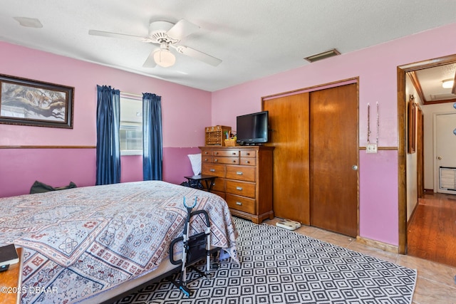tiled bedroom with attic access, a ceiling fan, visible vents, and a closet