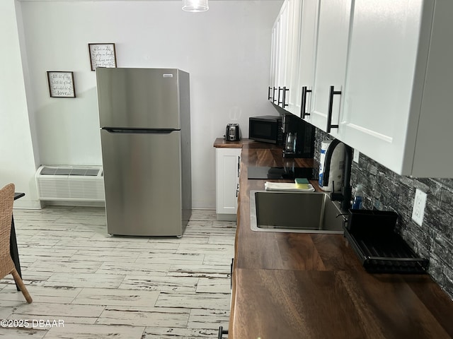 1909 S Atlantic Ave Unit 213, Daytona Beach, FL 32118 - kitchen with freestanding refrigerator, a sink, black microwave, white cabinets, and butcher block countertops