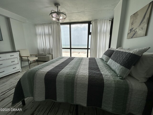 1909 S Atlantic Ave Unit 213, Daytona Beach, FL 32118 - bedroom with wood finished floors, a chandelier, and an AC wall unit