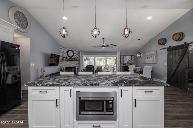 kitchen with stainless steel microwave, a barn door, freestanding refrigerator, and wood tiled floor