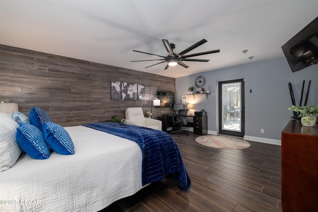 bedroom with baseboards, wood tiled floor, ceiling fan, wood walls, and an accent wall