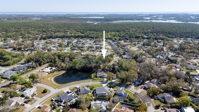 drone / aerial view featuring a wooded view, a water view, and a residential view