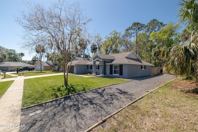 view of front of home featuring stucco siding, driveway, a front yard, and fence