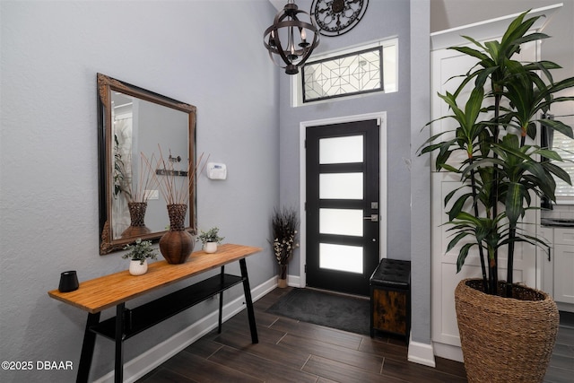 foyer with wood tiled floor, baseboards, a wealth of natural light, and a chandelier