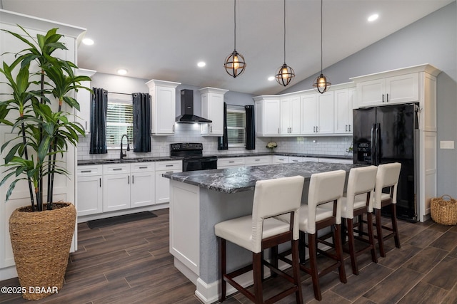 kitchen with wood finish floors, a sink, black appliances, wall chimney range hood, and a center island