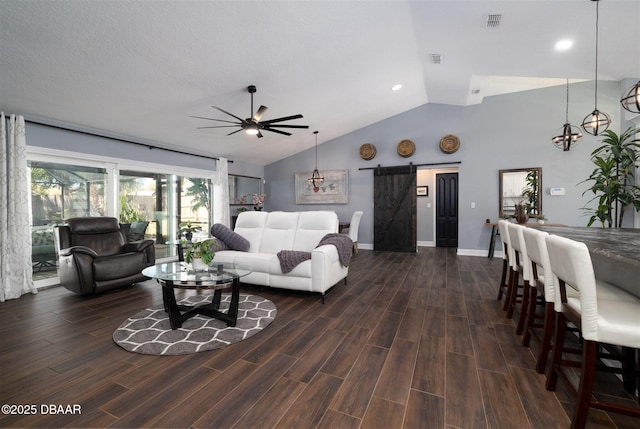 living area featuring visible vents, dark wood-type flooring, a barn door, lofted ceiling, and ceiling fan with notable chandelier