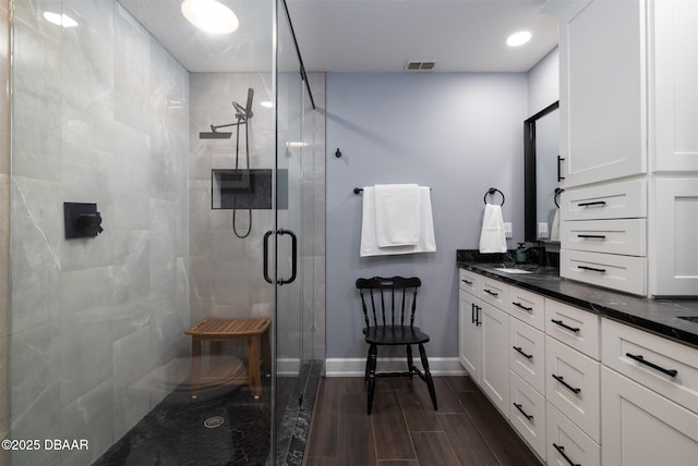 full bathroom featuring visible vents, baseboards, wood tiled floor, a stall shower, and vanity