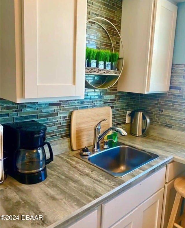 room details featuring white cabinets, sink, and decorative backsplash