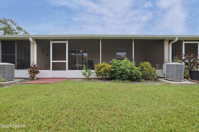 rear view of house featuring a lawn, a sunroom, and central AC unit