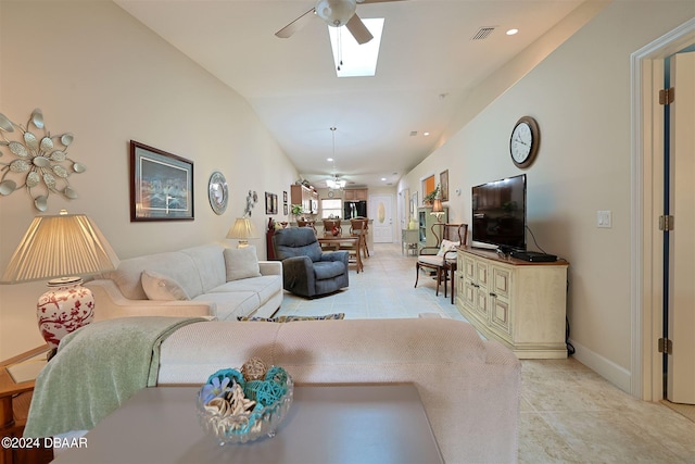 living room with ceiling fan, light tile patterned floors, and lofted ceiling with skylight